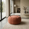 Ottoman rond terracotta en tissu, design moderne capitonné dans un salon lumineux et contemporain.