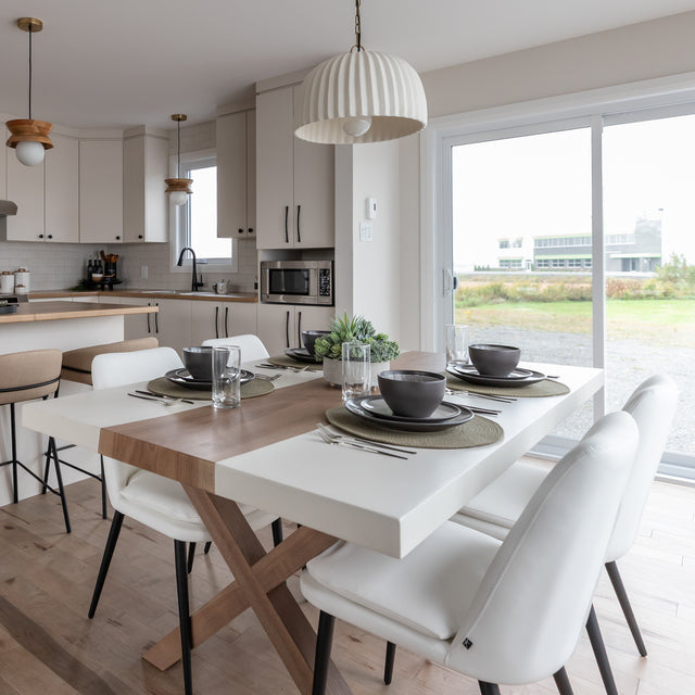 table de salle a manger moderne en bois et resine blanche avec pieds croises et chaises blanches a pieds noirs.
