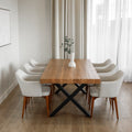 table a manger en bois massif avec pieds metalliques noirs et chaises blanches modernes dans salle lumineuse.