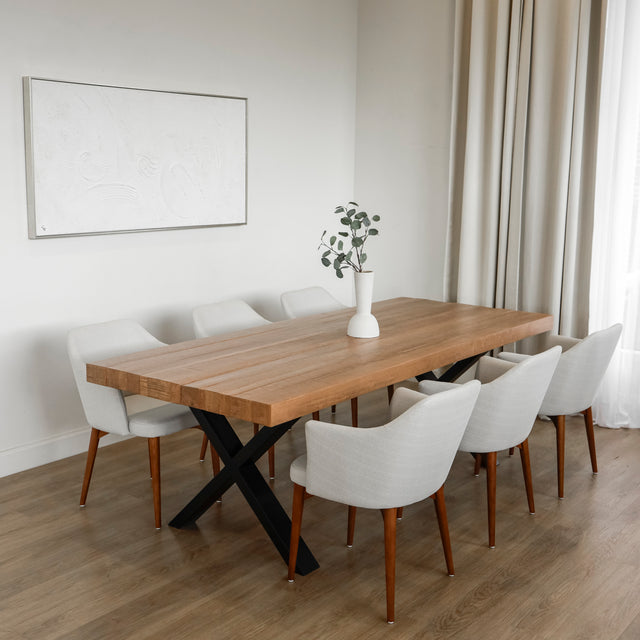 table a manger en bois massif avec pieds metalliques noirs et chaises blanches modernes dans salle lumineuse.