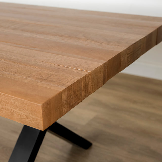 image rapprochée d'une table a manger en bois massif avec pieds metalliques noirs et chaises blanches modernes dans salle lumineuse.
