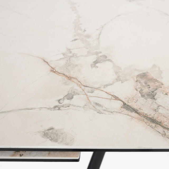 table extensible avec plateau effet marbre clair et pieds en metal noir.