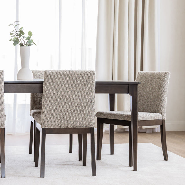 Table de salle à manger rectangulaire en bois foncé et chaises rembourrées beige au design contemporain.