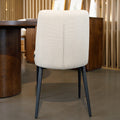 Chaise de salle à manger en tissu beige avec piètement noirs, placée près d’une table en bois dans un intérieur moderne.