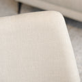 Chaise de salle à manger en tissu beige avec piètement noirs, placée près d’une table en bois dans un intérieur moderne.