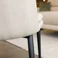 Chaise de salle à manger en tissu beige avec piètement noirs.
