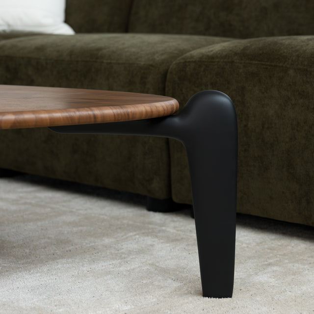 Table basse triangulaire en bois avec pieds noirs, au design contemporain dans un salon lumineux.