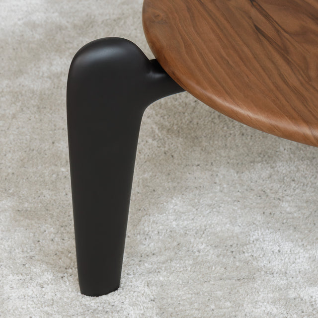 Table basse triangulaire en bois avec pieds noirs, au design contemporain dans un salon lumineux.