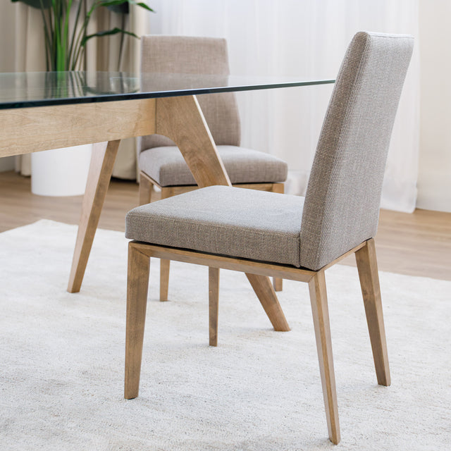 Chaise de cuisine en tissu beige avec structure en bois naturel près d’une table contemporaine.