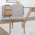 Chaise de cuisine en tissu beige avec structure en bois naturel près d’une table contemporaine.