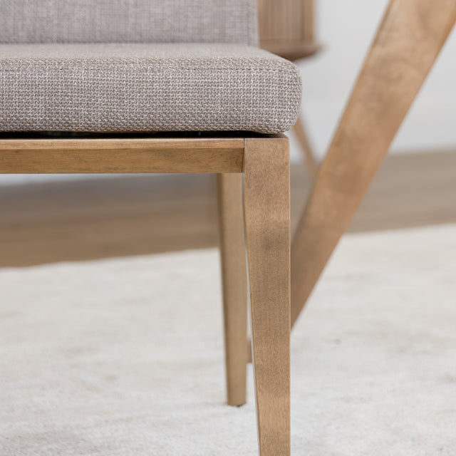 Chaise de cuisine en tissu beige avec structure en bois naturel près d’une table contemporaine.