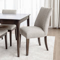 Chaise de salle à manger rembourrée en tissu beige avec pattes en bois foncé, style contemporain et confortable.