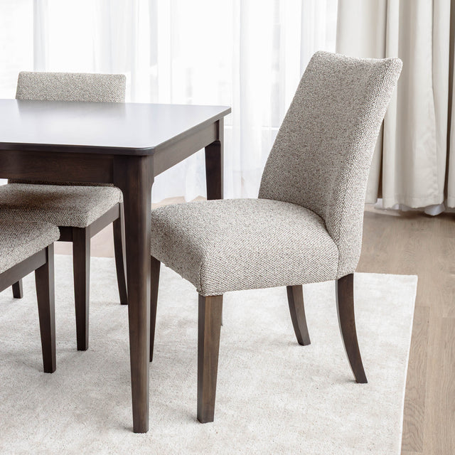 Chaise de salle à manger rembourrée en tissu beige avec pattes en bois foncé, style contemporain et confortable.