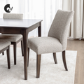 Chaise de salle à manger rembourrée en tissu beige avec pattes en bois foncé, style contemporain et confortable.