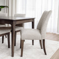 Chaise de salle à manger rembourrée en tissu beige avec pattes en bois foncé, style contemporain et confortable.
