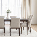 Chaise de salle à manger rembourrée en tissu beige avec pattes en bois foncé, style contemporain et confortable.