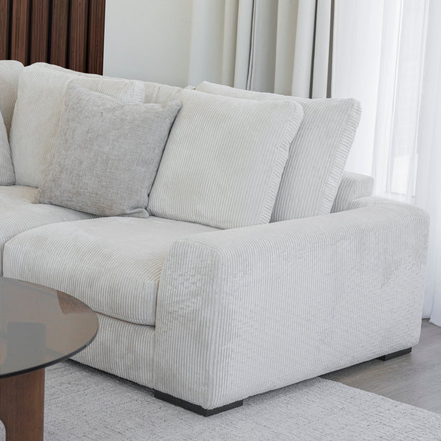 Modulaire d angle en tissu corduroy creme avec table basse en bois et decor minimaliste sur tapis clair.