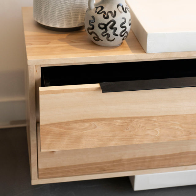 Meuble TV moderne en bois clair avec structure en béton blanc, rangements fermés et etagere ouverte, ideal pour salon contemporain.