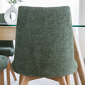 Chaise rembourrée en tissu vert avec dossier incurvé et pieds en bois, autour d’une table à manger au design moderne.