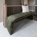 Banc en velours vert olive avec coussin beige a franges dans un interieur moderne.