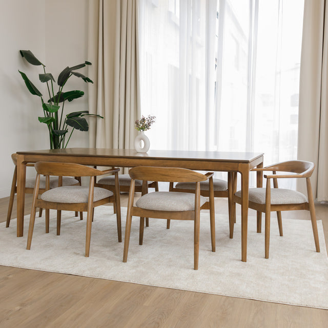 Table de cuisine en bois avec chaises rembourrées dans un intérieur minimaliste lumineux.
