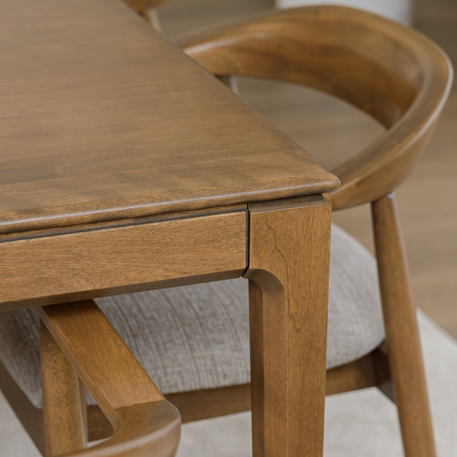 Table de cuisine en bois avec chaises rembourrées dans un intérieur minimaliste lumineux.