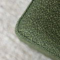 Détail ottoman carré vert en tissu texturé, finition soignée et angle net pour salon moderne.