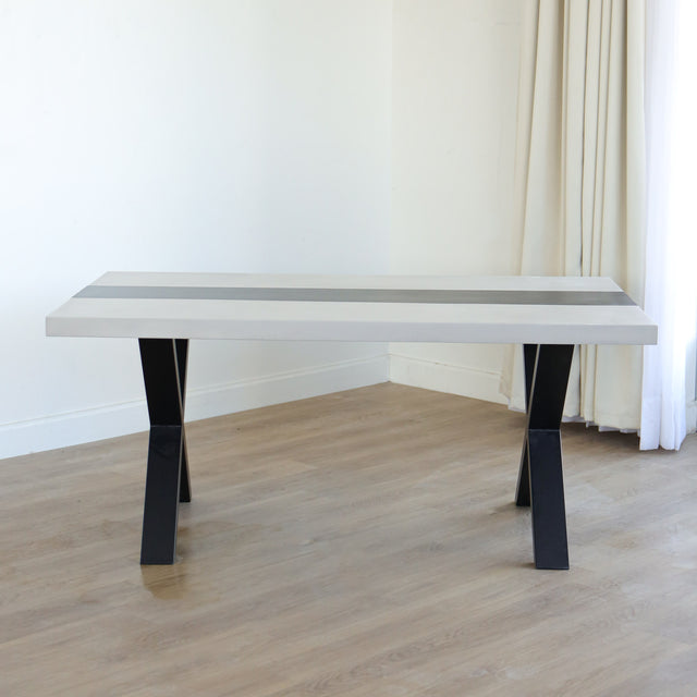 Table à manger moderne avec plateau béton ciment, tranche de frêne noir et piètement en métal noir, idéale pour salle à manger contemporaine.