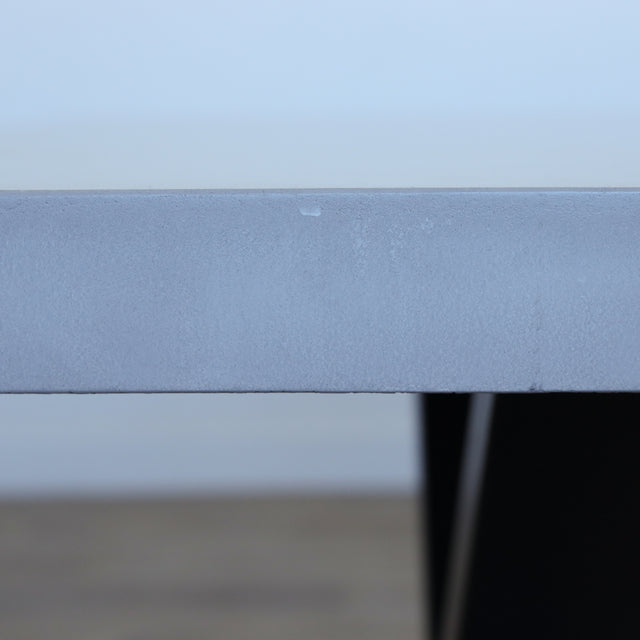 Table de salle à manger au design rectangulaire, plateau clair et piétement en X noirs, dans une salle à manger lumineuse.