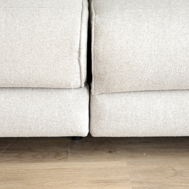 Image rapprochée d'un Sectionnel en tissu greige avec pattes noires, design moderne et assises confortables pour salon contemporain.