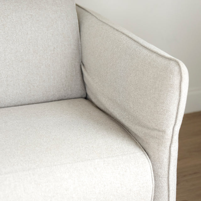 Image rapprochée d'un Sectionnel en tissu greige avec pattes noires, design moderne et assises confortables pour salon contemporain.