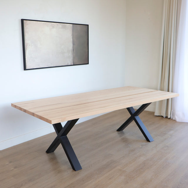 Table rectangulaire en bois clair avec pieds en metal noir en X, design industriel elegant.