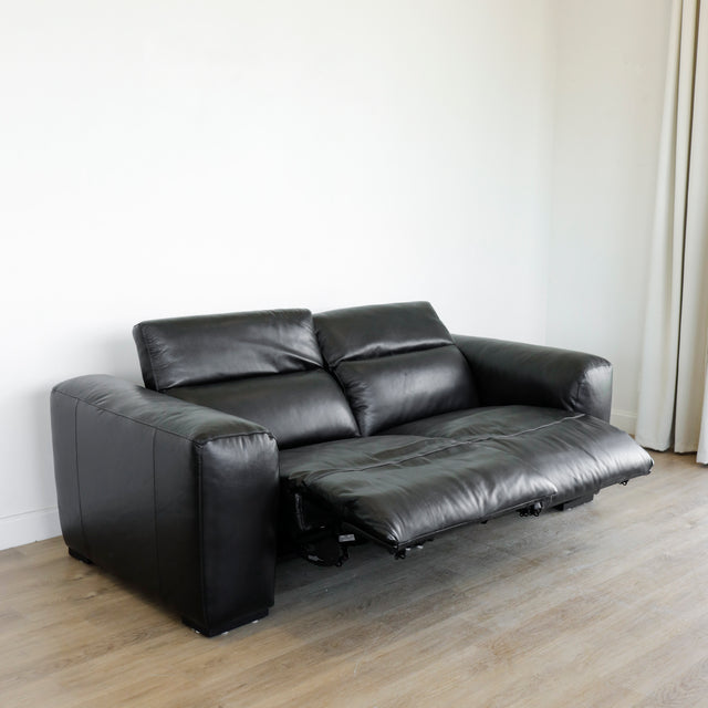 canape en cuir noir avec assise relax electrique et dossiers ajustables sur sol en bois clair.
