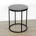 Table d’appoint ronde au design minimaliste, avec un plateau noir et une structure métallique fine de forme cylindrique, également noire.
