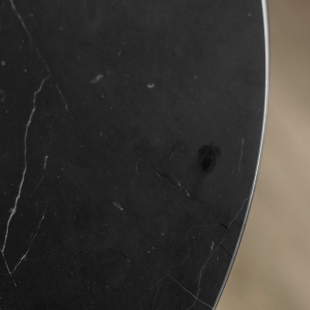 Gros plan d’un plateau circulaire en marbre noir avec de fines veines blanches naturelles, mettant en valeur la texture lisse et élégante de la pierre.
