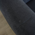 Detail de l assise du canape gris fonce en tissu matelasse au style moderne.
