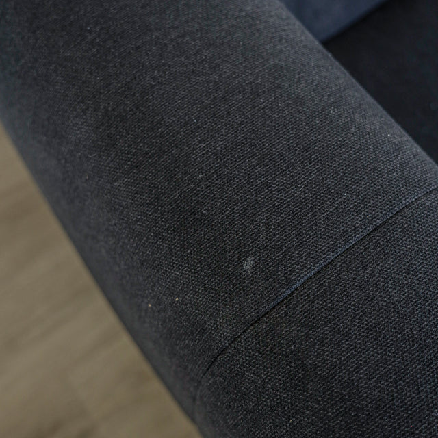 Detail de l assise du canape gris fonce en tissu matelasse au style moderne.
