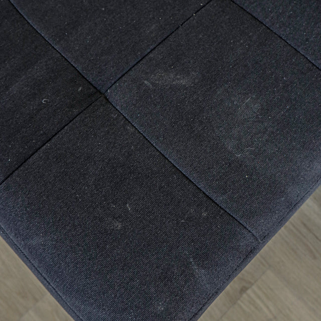 Detail de l assise du canape gris fonce en tissu matelasse au style moderne.
