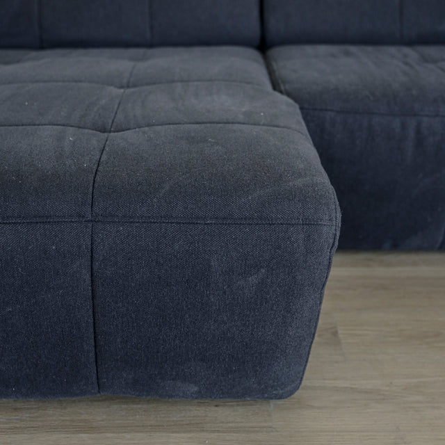 Detail de l assise du canape gris fonce en tissu matelasse au style moderne.
