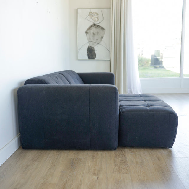 Canape d angle gris fonce matelasse au design moderne et lignes epurees.
