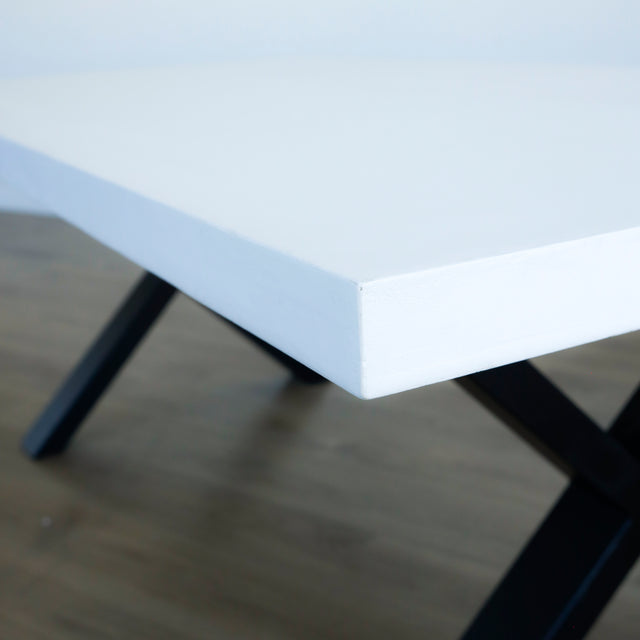gros plan d’un coin de plateau de table blanc mat, montrant une texture lisse avec des irrégularités légères le long du bord.
