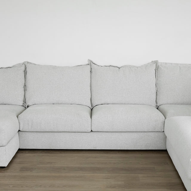 canape gris clair avec grands coussins d assise et de dossier sur sol en bois.
