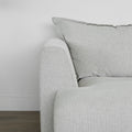 vue detaillee d un canape gris clair avec accoudoir arrondi et coussin moelleux.
