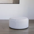 ottoman rond en tissu blanc bouclé avec plateau en bois amovible sur sol en bois.