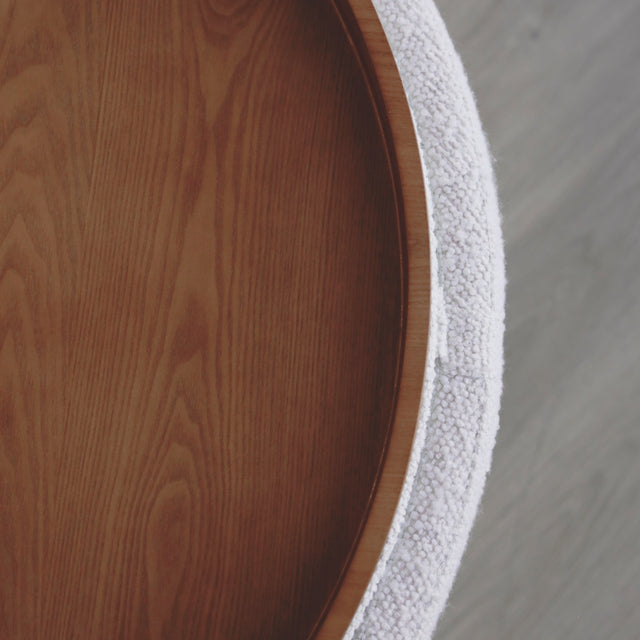 image rapprochée d'un ottoman en tissu blanc bouclé avec plateau amovible en bois noyer.