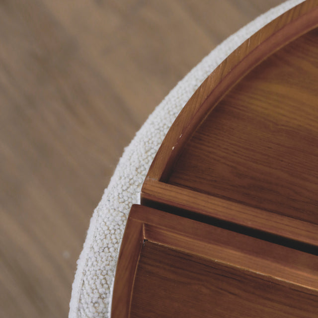 image rapprochée d'un ottoman en tissu blanc bouclé avec plateau amovible en bois noyer.