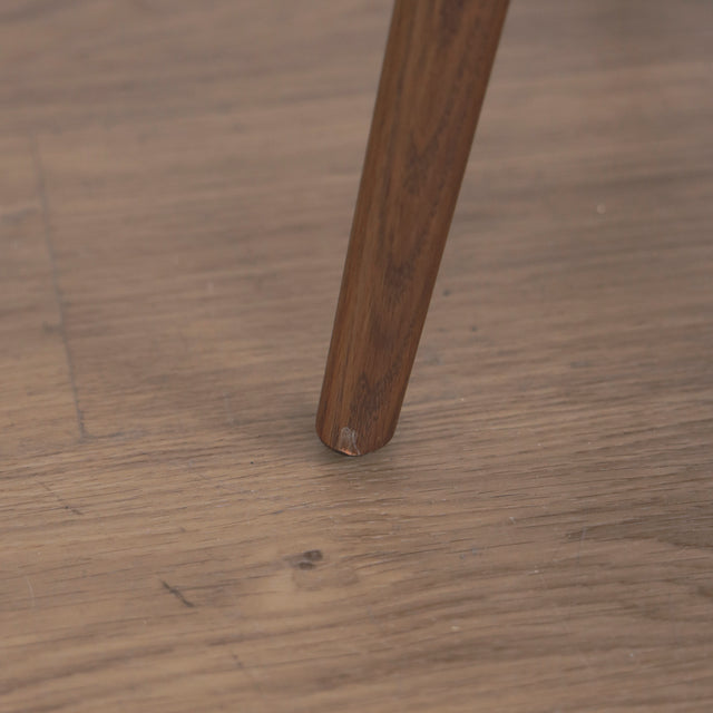 Image rapprochée d'une patte comportant un défaut d'un ensemble de deux chaises en cuir beige avec pattes en bois teinture noyer