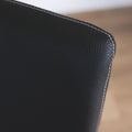 image rapprochée d'un ensemble de chaises moderne en cuir noir avec coutures blanches et pieds en bois sombre.