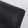 Image rapprochée d'un Fauteuil moderne en cuir noir avec dossier capitonne et pieds en bois fonce.