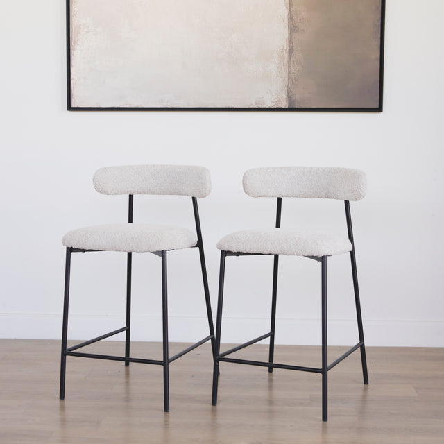 Paire de tabourets en tissu crème bouclé avec pieds metalliques noirs.
